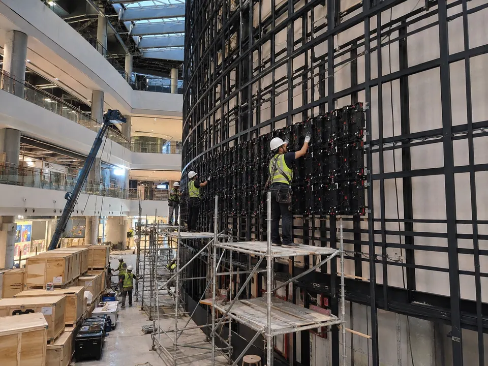 Installer fixing an LED cabinet frame from scaffolding on site
